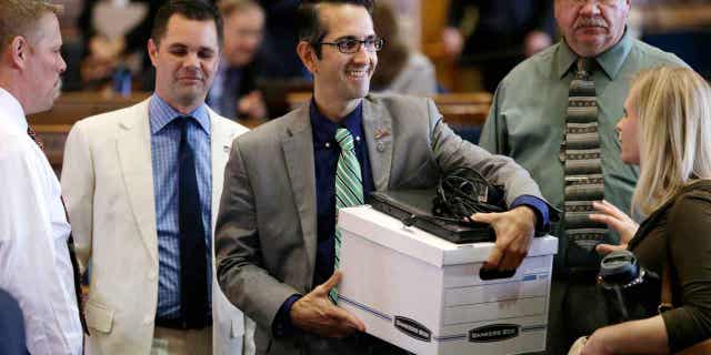Rep. Joel Fry, center, carries a box from his desk on June 5, 2015, in Des Moines, Iowa. Thousands of Iowa residents would be expected to lose food stamp and Medicaid benefits under a bill given final legislative approval on April 13, 2023. Fry said the bill takes nothing away from people who are eligible for the benefits.