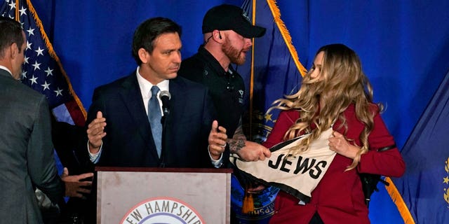 A protester interrupts an address by Florida Gov. Ron DeSantis during a stop at a New Hampshire Republican Party dinner, Friday, April 14, 2023, in Manchester, N.H. 
