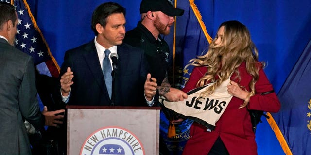 A protester interrupts an address by Florida Gov. Ron DeSantis during a stop at a New Hampshire Republican Party dinner, Friday, April 14, 2023, in Manchester, N.H. 