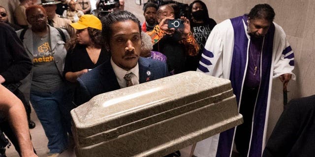 Rep. Justin Jones carries a casket through the halls of the state Capitol with Rev. William J. Barber, Monday, April 17, 2023, in Nashville, Tennessee.
