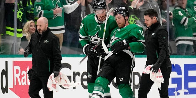 Dallas Stars' Joe Pavelski, second from right, is helped off the ice by Mason Marchment and staff after suffering an unknown injury in the second period of Game 1 of an NHL hockey Stanley Cup first-round playoff series against the Minnesota Wild, Monday, April 17, 2023, in Dallas.