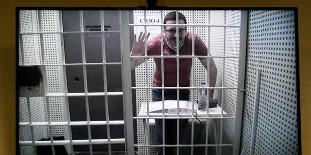 Russian opposition activist Ilya Yashin is seen on a tv screen from a video link provided by the Russian Federal Penitentiary Service in a courtroom of the Moscow City Court during a hearing on his appeal of his prison sentence, in Moscow, Russia, on April 19, 2023. 