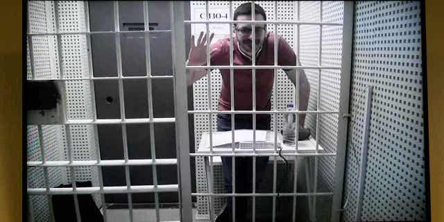Russian opposition activist Ilya Yashin is seen on a tv screen from a video link provided by the Russian Federal Penitentiary Service in a courtroom of the Moscow City Court during a hearing on his appeal of his prison sentence, in Moscow, Russia, on April 19, 2023.