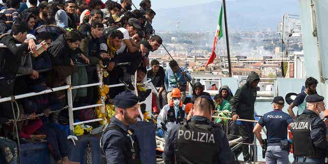 Migrants disembark from a ship in the Sicilian port of Catania