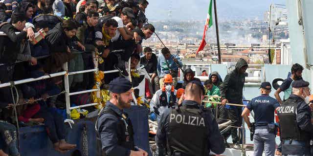 Migrants disembark from a ship in the Sicilian port of Catania