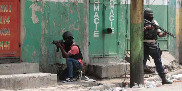 Police officers take cover during an anti-gang operation in Haiti