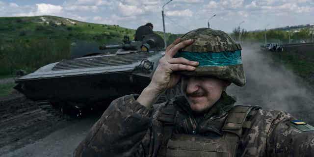 A Ukrainian soldier holds his helmet 