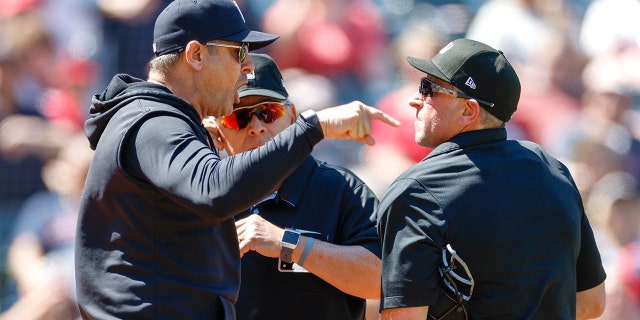 Aaron Boone, de los Yankees de Nueva York, a la izquierda, argumenta una apelación de revisión con los árbitros del plato Chris Guccione, a la derecha, y Larry Vanover después de ser expulsado de un juego en la primera entrada en el Progressive Field el 12 de abril de 2023, en Cleveland.