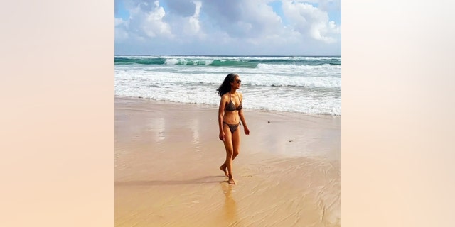 Nina Cash walking on the beach in a bikini