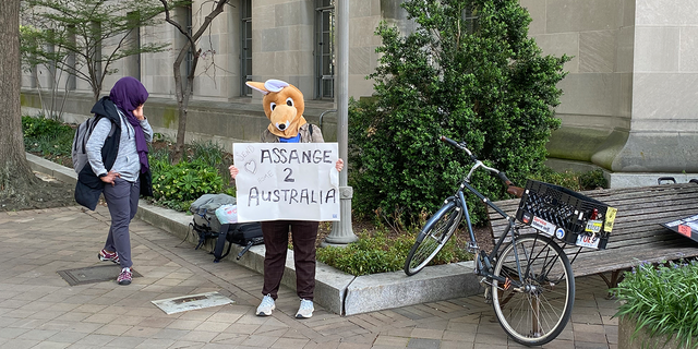 A woman in a kangaroo mask is holding sign in support of Julian Assange.