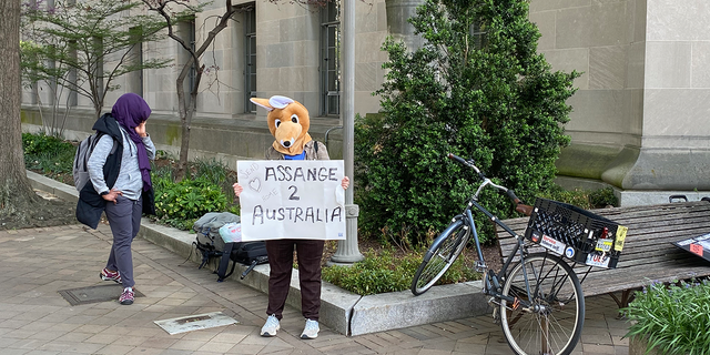 A woman in a kangaroo mask is holding sign in support of Julian Assange.