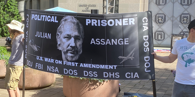 Supporters of Julian Assange hold a sign in support of the Wikileaks founder at a rally at the Justice Department.