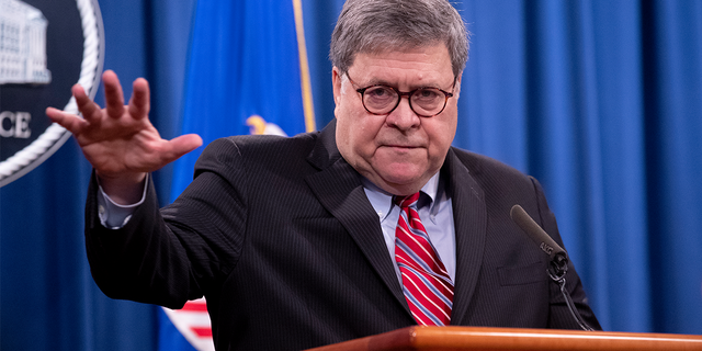 Bill Barr right hand raised at lectern at a briefing