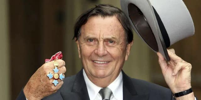 Barry Humphries tạo dáng chụp ảnh sau khi nhận được Huân chương Xuất sắc nhất của Đế quốc Anh từ Nữ hoàng Anh Elizabeth II