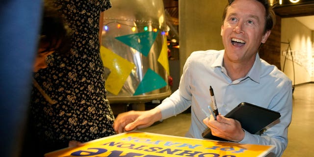 Denver mayoral candidate Mike Johnston autographs yard signs before entering an election eve watch party on April 4, 2023, in a lower downtown hotel.