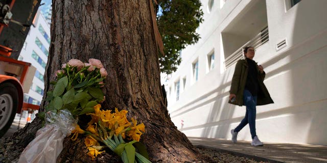 A woman walks past flowers left outside an apartment building where a technology executive was fatally stabbed in San Francisco, Tuesday, April 4, 2023. Bob Lee was a technology executive who created Cash App and was currently chief product officer of MobileCoin.
