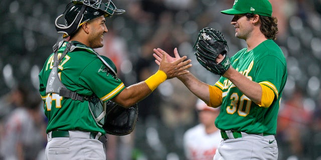 Oakland Athletics catcher Carlos Perez and relief pitcher Chad Smith celebrate their team's win over the Orioles, Wednesday, April 12, 2023, in Baltimore.