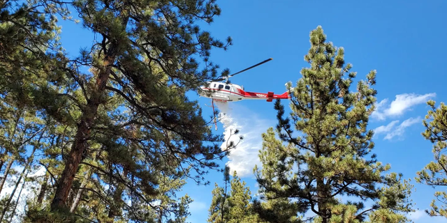 A firefighting helicopter drops fire retardant over Fire 403, which is 25 percent containment. 