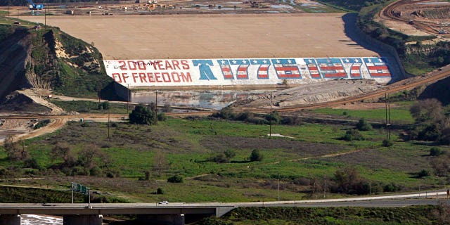 Seen is the Prado Dam with its bicentennial mural at a time when crews were working to close a breach in the dam, at left, due to heavy rains in Corona, California, on Jan. 14, 2005.