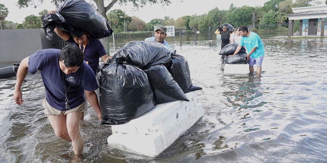 People wade through water trying to save valuables in a Fort Lauderdale, Florida, neighborhood on April 13, 2023, after an unprecedent storm flooded the area within hours.