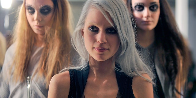 Fashion designer Katie Gallagher stands in front of two of her models