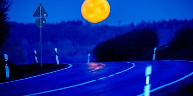 An empty road is pictured near Wehrheim near Frankfurt, Germany, as the moon sets, early Tuesday, April 4, 2023. 