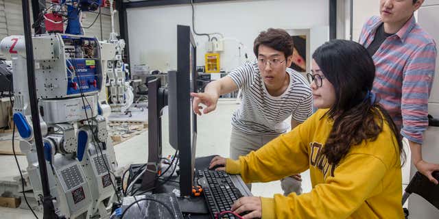 Mahasiswa di universitas KAIST di Seoul, Korea Selatan, memindai perangkat lunak AI di dalam pusat penelitian robot humanoid.