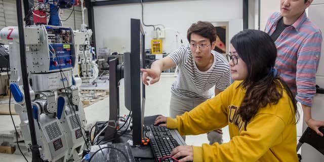 Students at KAIST university in Seoul, South Korea, scan AI software inside a research center for humanoid robots.