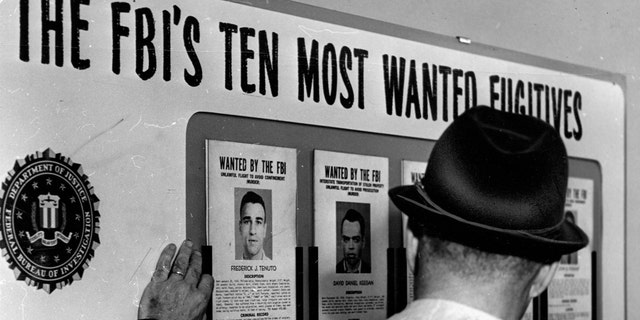 An FBI Special Agent checks the "ten most wanted fugitives" list at the Boston FBI office