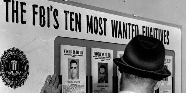 An FBI Special Agent checks the "ten most wanted fugitives" list at the Boston FBI office