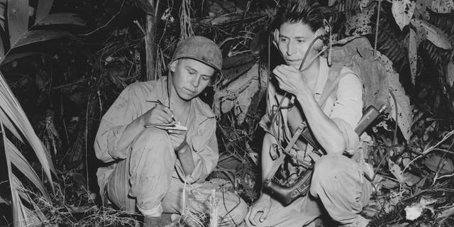 Corporal Henry Bake Jr., left, and Private First Class George Kirk, right, were Navajo Indians serving with a Marine Signal unit. Here, they operate a portable radio set in a clearing they've hacked in the dense jungle, close behind the front lines on the island of Bougainville, Papua New Guinea, December 1943.