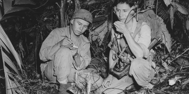 Corporal Henry Bake Jr., left, and Private First Class George Kirk, right, were Navajo Indians serving with a Marine Signal unit. Here, they operate a portable radio set in a clearing they've hacked in the dense jungle, close behind the front lines on the island of Bougainville, Papua New Guinea, December 1943.