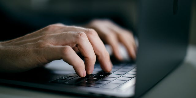 Man types on a laptop keyboard