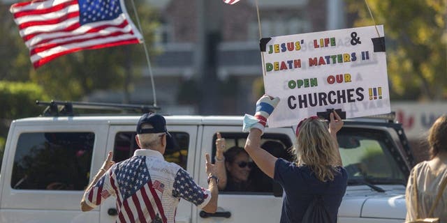 A woman holds a sign calling to "open our churches"