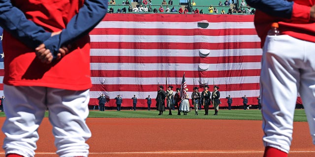 The giant American flag was unfurled over the Green Monster during the national anthem. The Boston Red Sox hosted the Minnesota Twins in the annual Patriots' Day morning MLB baseball game at Fenway Park in Boston on April 18, 2022.