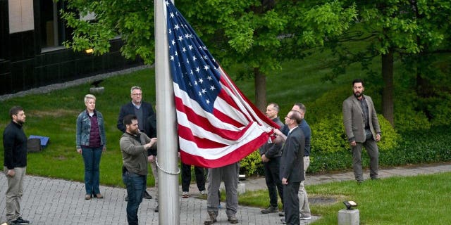 TOPSHOT - Employees rise up the flag outside the U.S. embassy in Kyiv on May 18, 2022, as the embassy reopens after being closed for three months due to the Russian invasion.