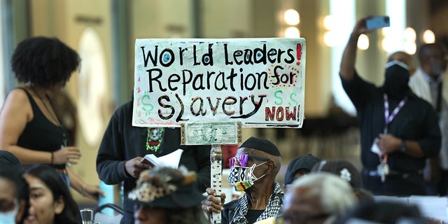 A Los Angeles resident holds up a sign demanding reparations for slavery