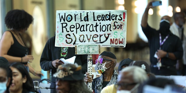 LA resident holds up sign demanding reparations for slavery