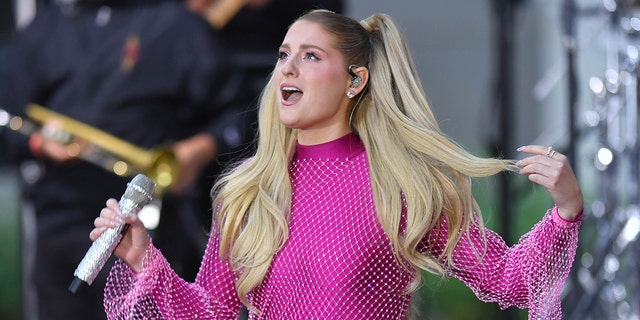 Meghan Trainor in a magenta sparkly jumpsuit singing on stage with pigtails in New York