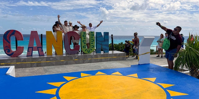 Cancun sign with tourist posing 