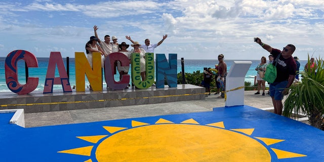 Cancun sign with tourist posing 