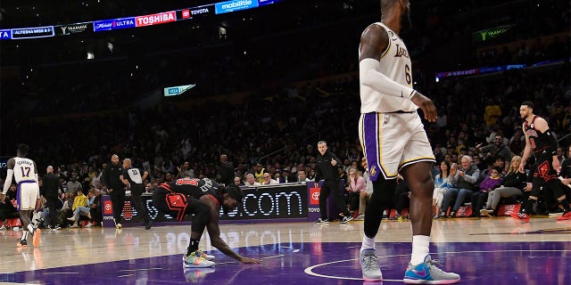 Patrick Beverley (21) of the Chicago Bulls touches the Los Angeles Lakers' court as he celebrates after scoring a basket against LeBron James (6) of the Lakers in the closing minute of a game at Crypto.com Arena March 26, 2023, in Los Angeles.