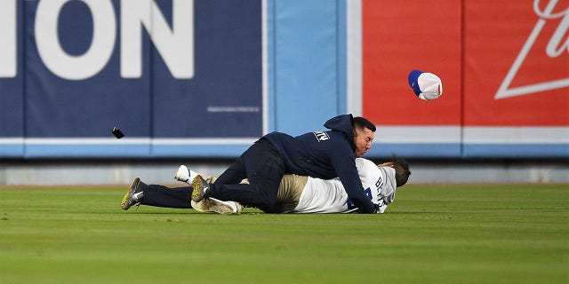 Un fanático de los Dodgers es atacado por seguridad cuando intenta proponerle matrimonio a su novia en las gradas durante el juego de la MLB entre los Diamondbacks de Arizona y los Dodgers de Los Ángeles el 30 de marzo de 2022 en el Dodger Stadium de Los Ángeles, California. 