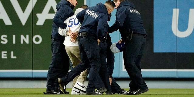 Security unit   region   a Dodger instrumentality   who ran onto the outfield during the crippled  against the Arizona Diamondbacks astatine  Dodger Stadium connected  March 30, 2023, successful  Los Angeles, California. 