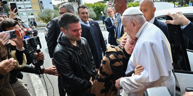 Papa Franjo grli Serenu Subaniu dok njezin suprug Matteo Rugghia (L) reagira, par koji je dan ranije izgubio svoje petogodišnje dijete, dok Papa napušta bolnicu Gemelli 1. travnja 2023. u Rimu, nakon što je otpušten nakon liječenja za bronhitis.