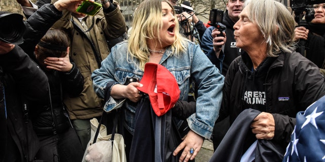 The Trump supporter engages in a verbal exchange with a protester with the words "ARREST TRUMP" on their shirt.