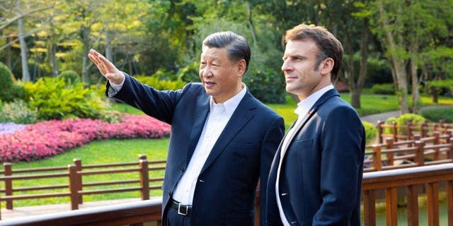 El presidente chino, Xi Jinping, a la izquierda, y el presidente francés, Emmanuel Macron, disfrutan del paisaje de un jardín chino en Guangzhou, China, el 7 de abril de 2023.