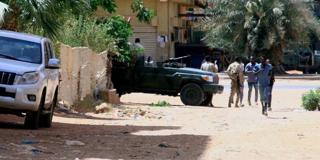 La gente pasa junto a un vehículo militar en Jartum el 15 de abril de 2023, en medio de enfrentamientos que, según informes, tuvieron lugar en la ciudad.
