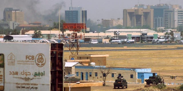 Kendaraan militer terlihat mengepulkan asap di atas gedung-gedung di sekitar bandara Khartoum pada 15 April 2023, di tengah bentrokan di kota tersebut.