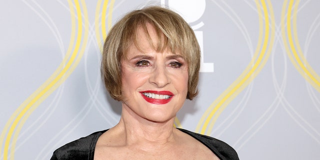 Patti LuPone smiles on the Tony Awards red carpet in a square cut, black dress and red lipstick